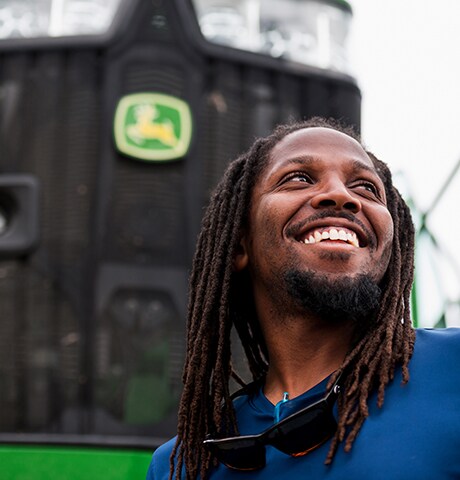 Smiling employee stands in front of a tractor